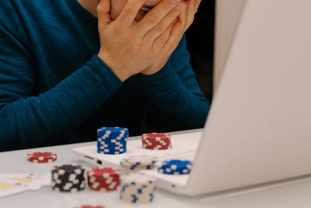 Worried person in front of laptop with gambling chips